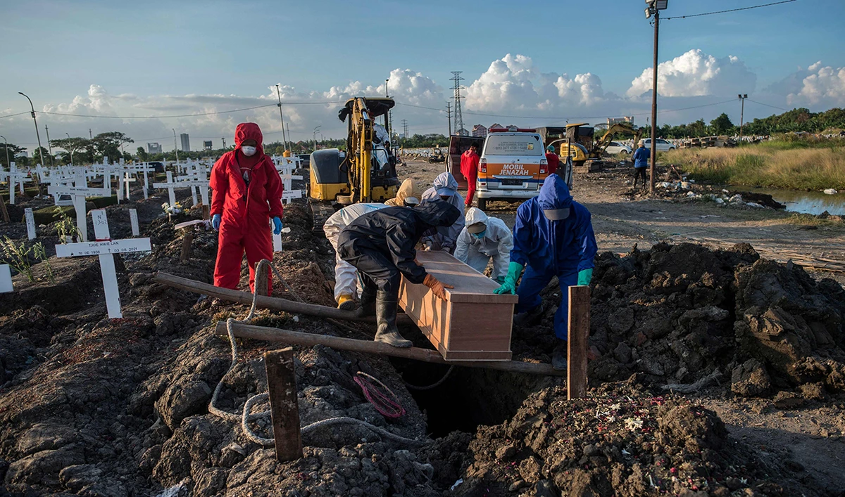 Grave diggers bury a coffin of a Covid-19 coronavirus victim at a cemetery in Surabaya on August 9, 2021. (AFP)