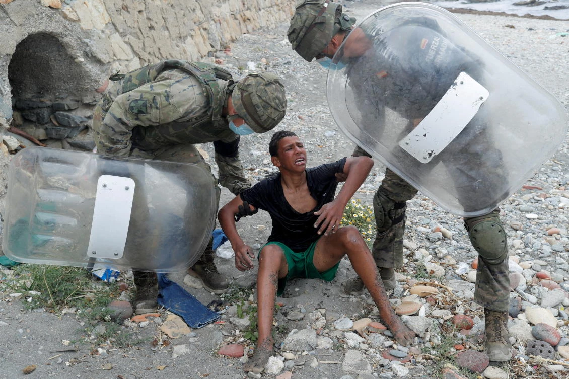 A Moroccan boy cries as he is helped by Spanish soldiers after he swam using bottles as a float, at El Tarajal beach, near the fence between the Spanish-Moroccan borders in Ceuta in May 19. (Reuters)