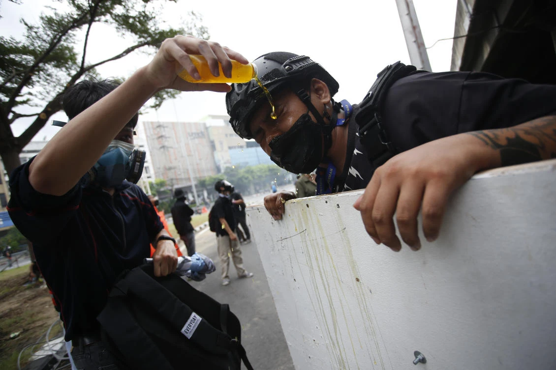 An anti-government protester has his eyes rinsed with water after tear gas was used during protest in Bangkok, Thailand, Friday, Aug. 13, 2021. (AP)