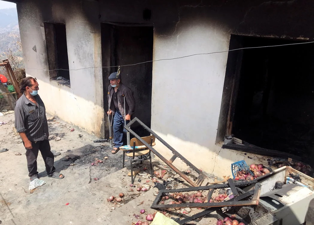 Lyazid Tazibt stands with his brother Khelaf at their burnt home following a wildfire in Ait Sid Ali village in Algeria on Monday. (Reuters)