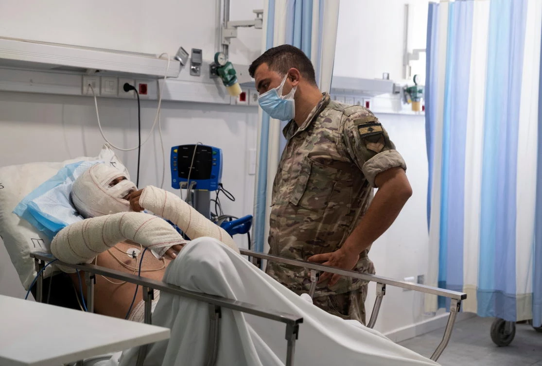 An army soldier stands next to a man injured during a fuel tank explosion in Akkar as he receives treatment at a hospital in Beirut on Sunday. (Reuters)