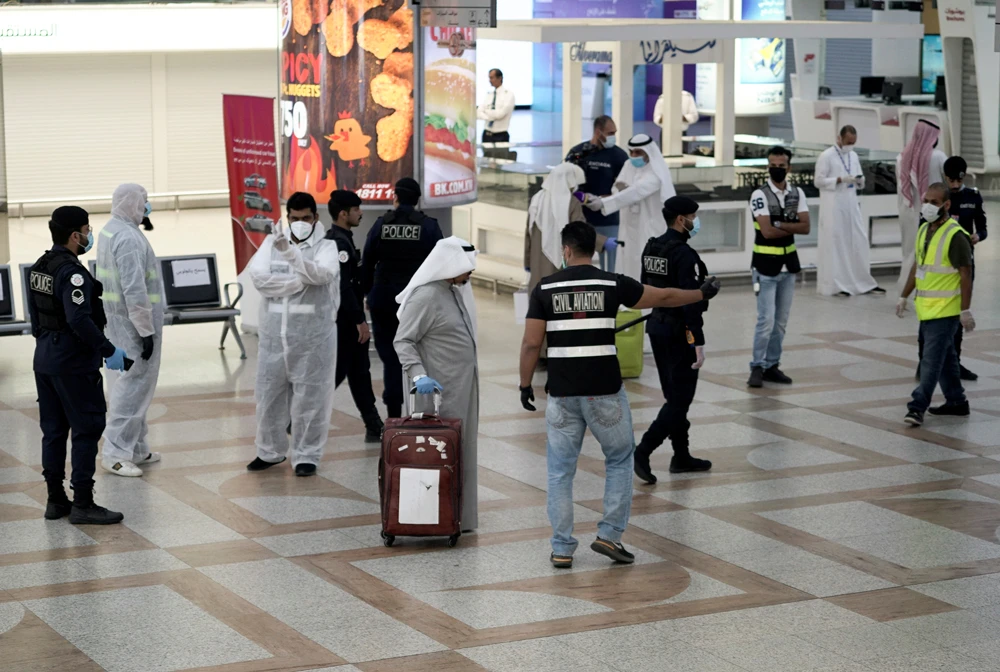 A Kuwaiti passenger walks by police and civil aviation personnel upon his arrival from Amman at Kuwait Airport, following the outbreak of COVID-19, in Kuwait City, Kuwait, April 21, 2020. (Reuters)
