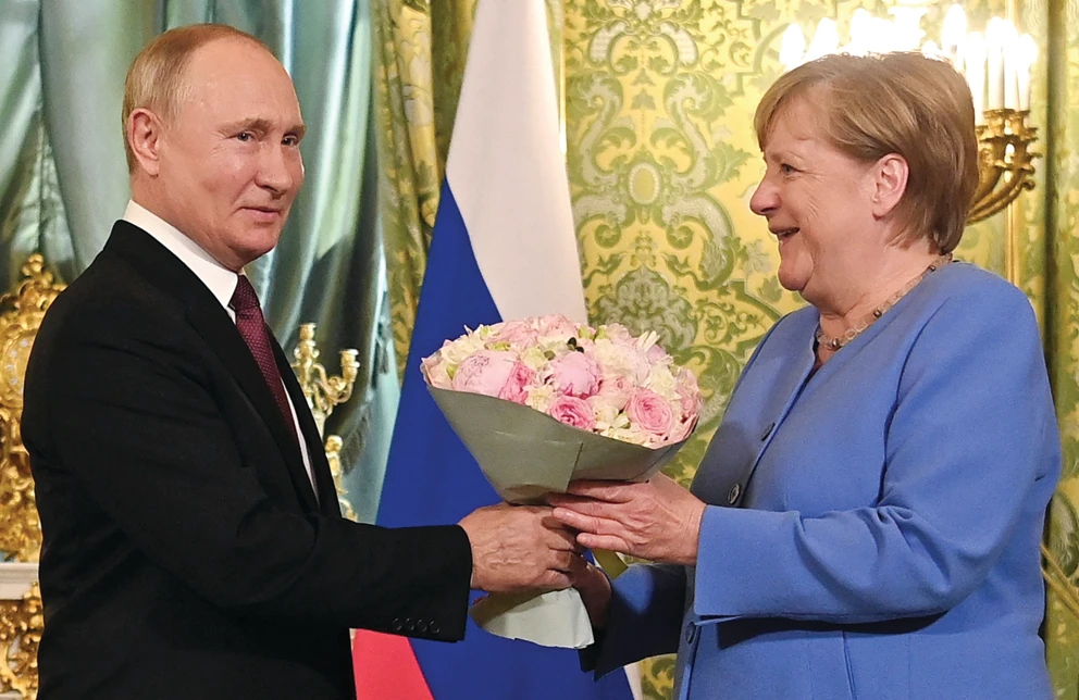 Russian President Vladimir Putin welcomes German Chancellor Angela Merkel with a bouquet of flowers during their meeting at the Kremlin in Moscow on Friday. (AFP)