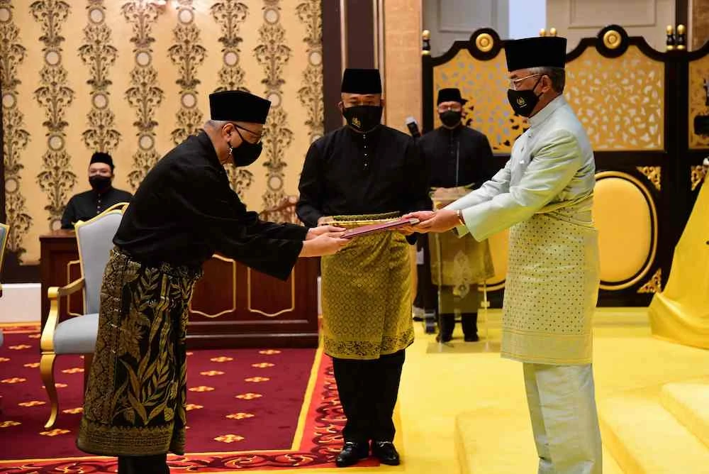 Incoming Prime Minister Ismail Sabri Yaakob, left, receives documents from King Sultan Abdullah Sultan Ahmad Shah, right, before taking the oath as Malaysia’s new leader. (Malaysia’s Department of Information/AFP)