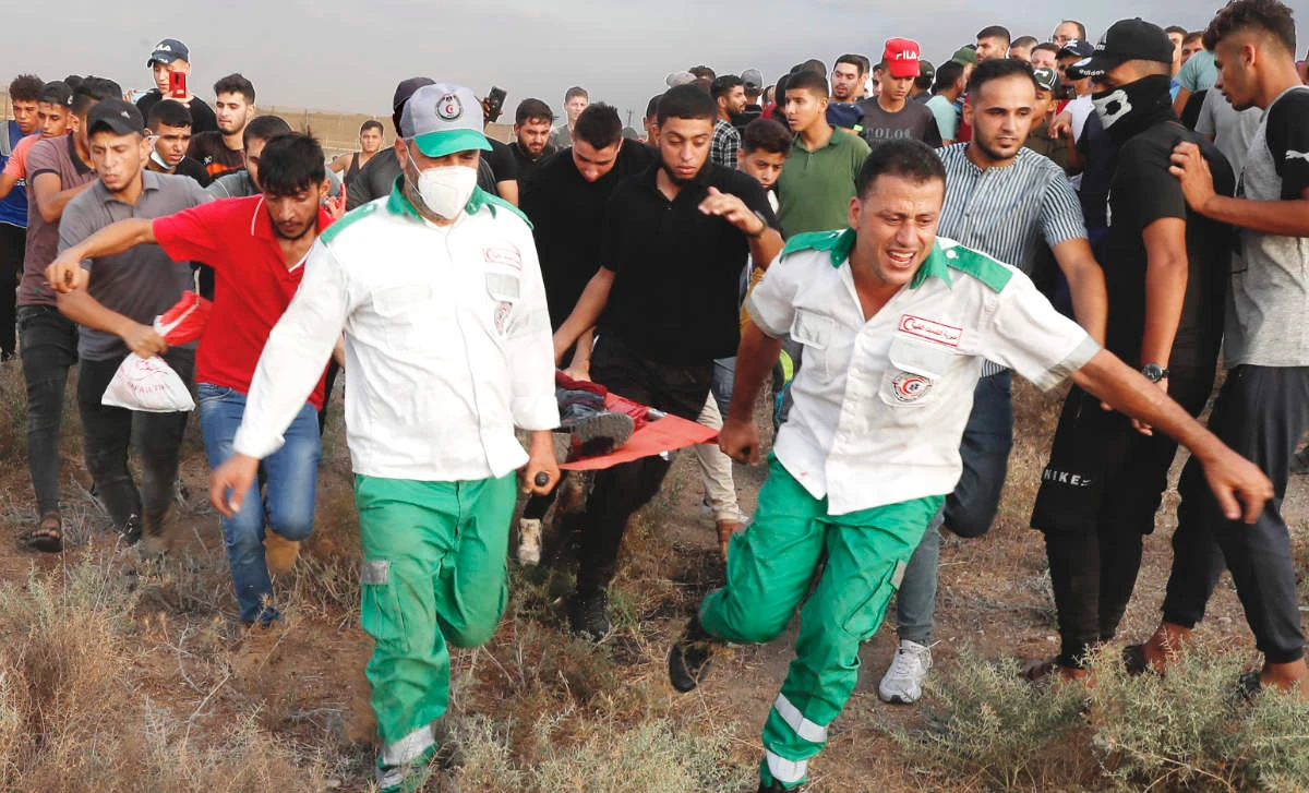 Medics evacuate a wounded person from the fence of Gaza Strip border during Saturday’s protest to mark the burning 52 years ago of Al-Aqsa Mosque. (AP)