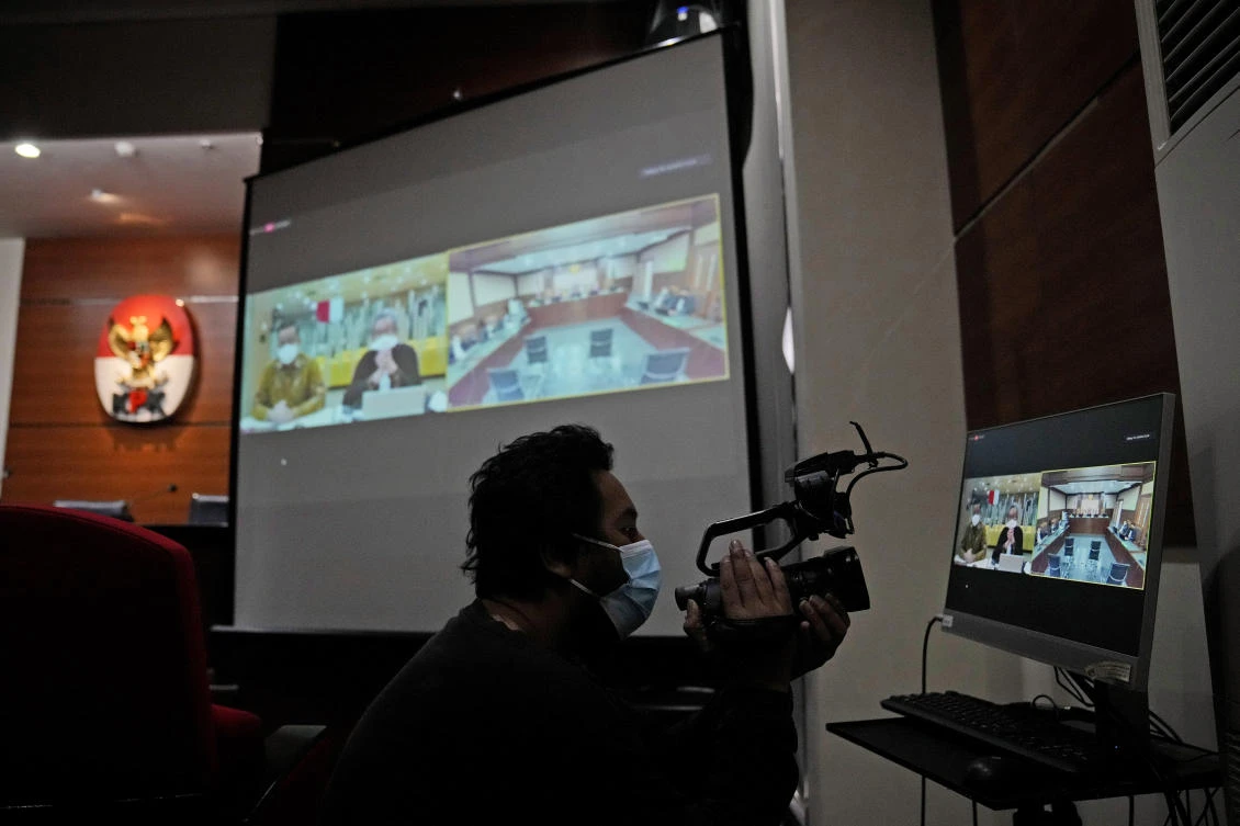 A journalist takes a video of a screen showing the live-streaming of the sentencing hearing of former Social Affairs Minister Juliari Peter Batubara held at the Corruption Eradication Commission building in Jakarta, Indonesia, Monday, Aug. 23, 2021. (AFP)