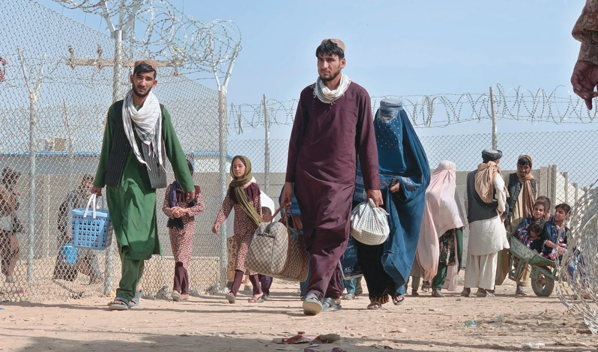 Afghans walk through a security barrier as they enter Pakistan through a border crossing point in Chaman, Pakistan, on Thursday. Pakistanis and Afghans cross the border daily. (AP)