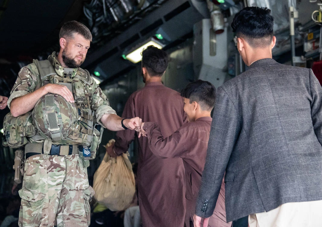 A member of the UK Armed Forces fist-bumping an evacuee during their deployment to support the evacuation of British nationals and entitled personel at Kabul airport in Afghanistan. (File/AFP)