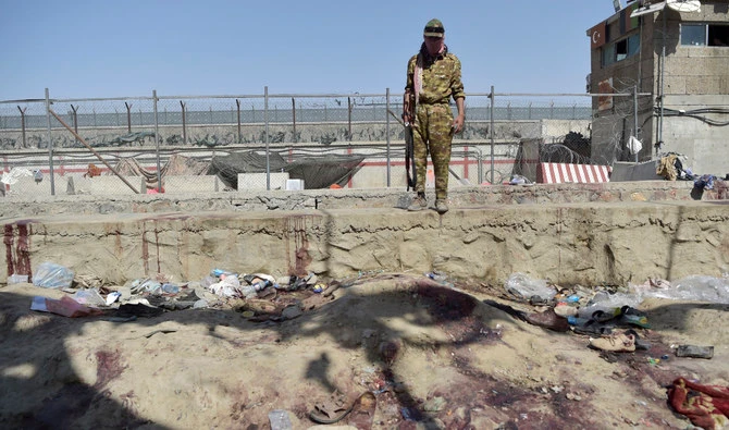 A Taliban fighter stands guard at the site of the August 26 twin suicide bombs, which killed scores of people including 13 US troops, at Kabul airport on August 27, 2021. (AFP)