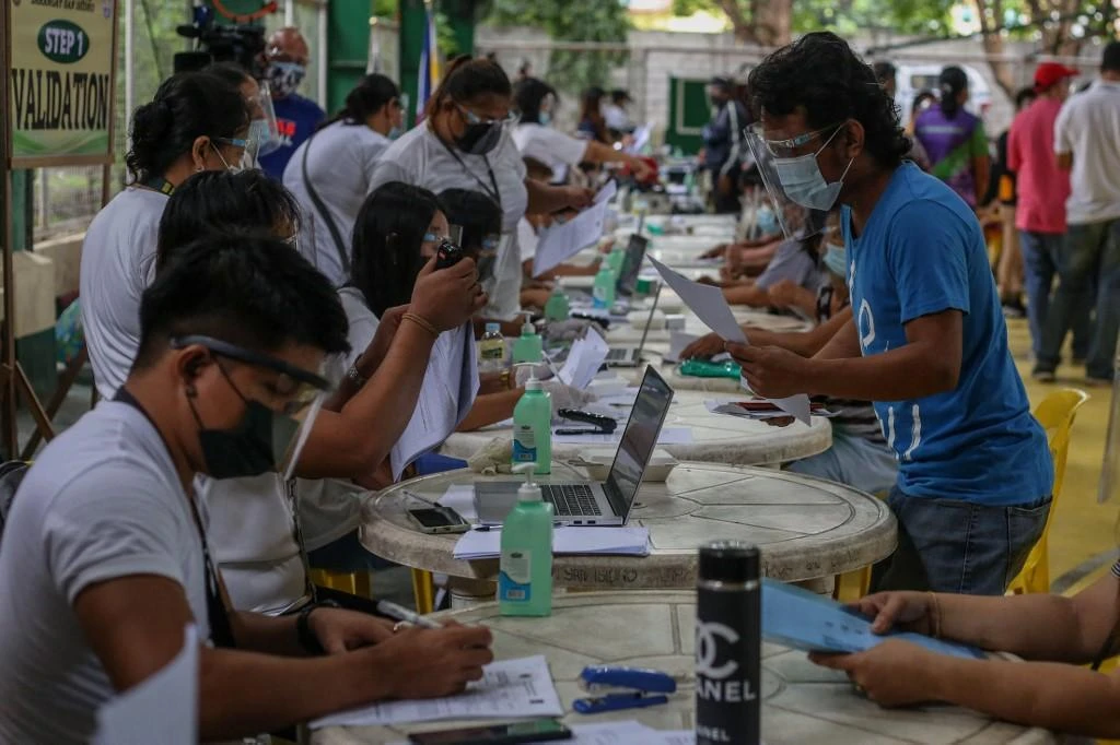 Individuals line up to receive cash aid from the Philippine national government during enhanced community quarantine in Manila. (AFP)
