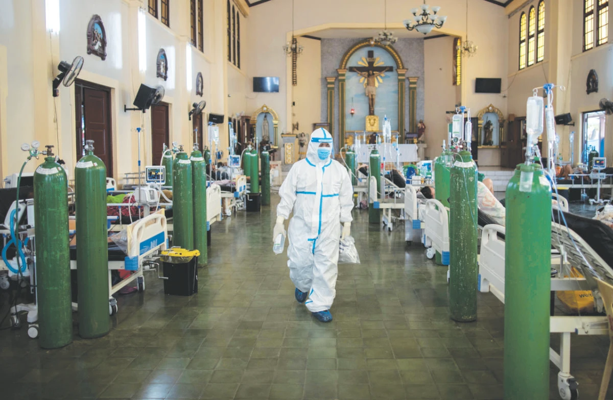 A health worker walks around to check on coronavirus disease patients admitted in the chapel of Quezon City General Hospital turned into a COVID-19 ward, in Quezon City, Philippines, August 20, 2021. (REUTERS)