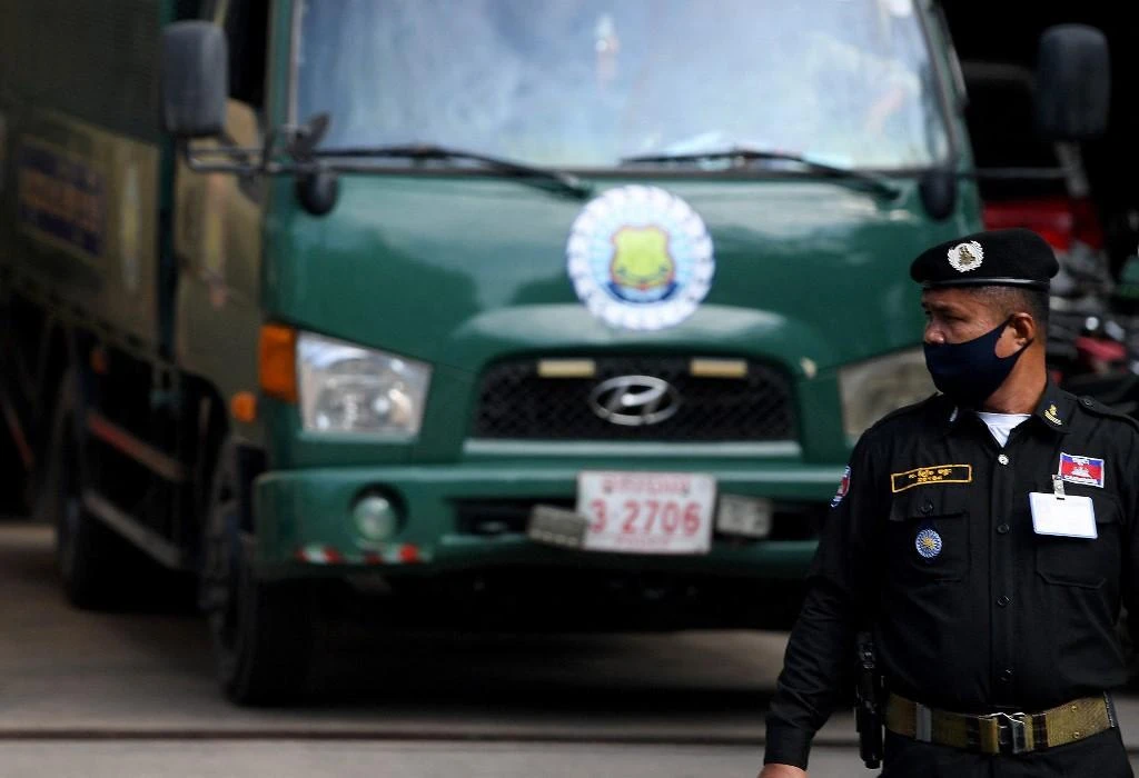 A policeman looks on as prisoners arrive in a truck at Phnom Penh Municipal Court in Phnom Penh, Vietnam on Aug. 18, 2021. (AFP)