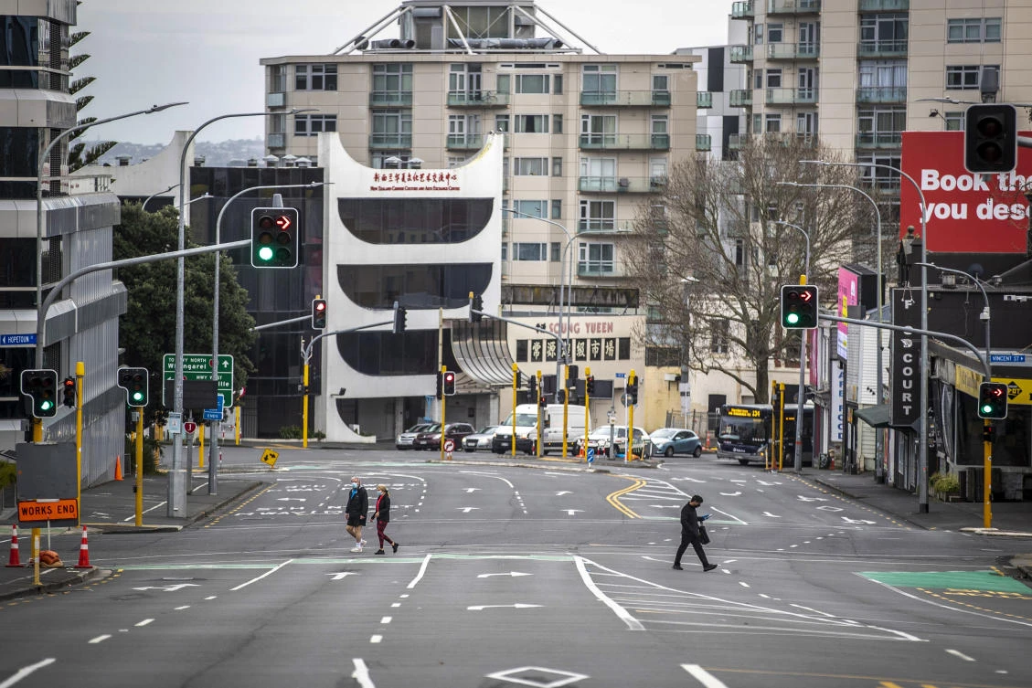 Around 1.7 million Aucklanders will remain in strict level 4 lockdown for another two weeks. Above, people cross nearly empty streets in the central business district of Auckland. (NZ Herald via AP)