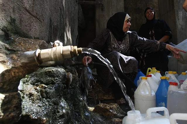 Palestinian women fill bottles with water in the West Bank village of Qarawah Bani Zeid. (Getty Images)