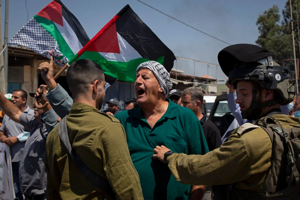 A Palestinian woman argues with Israeli soldiers during a protest against the creation of a new road for Israeli settlers near the village of Beita in the West Bank on Aug. 25, 2021. (AP Photo/Majdi Mohammed)