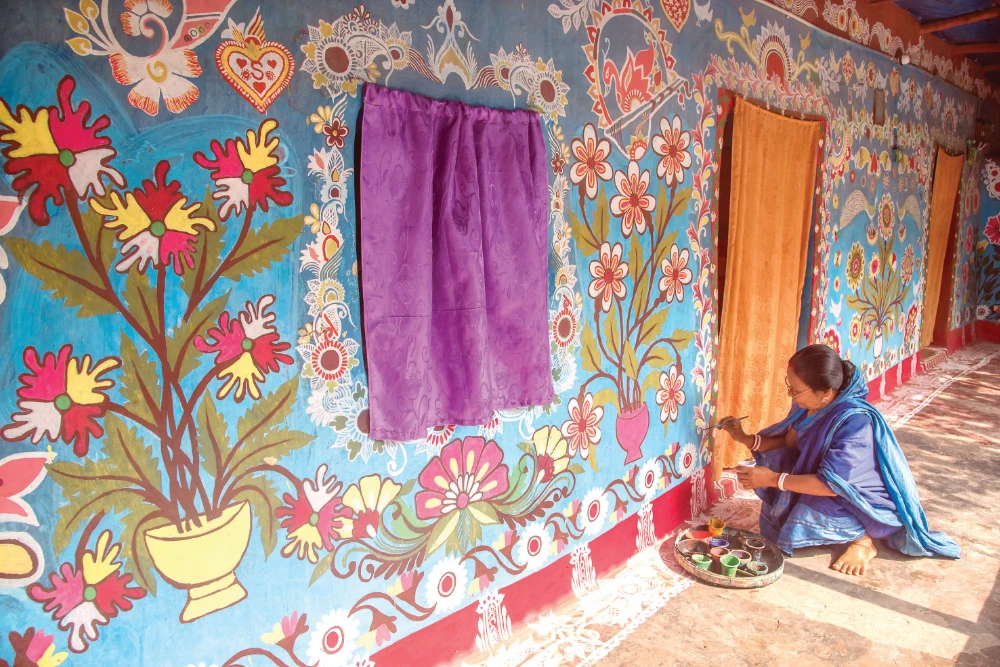 Daykhon Barman does art work on her house in Tikoli, Chapainawabganj district, northwestern Bangladesh. Other women followed Daykhon’s lead. (Supplied)