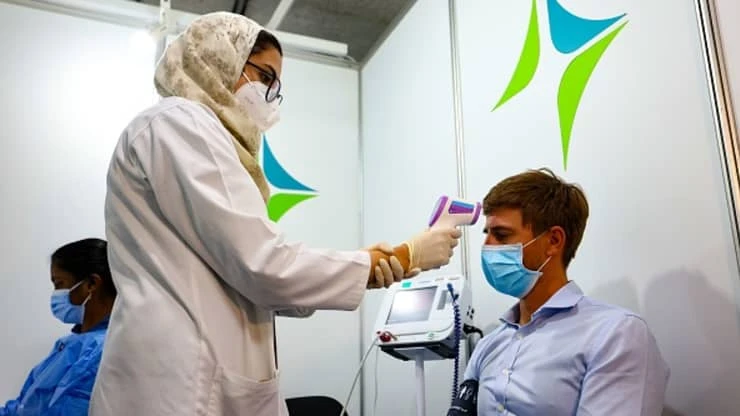 A health worker checks a man’s temperature before receiving a dose of vaccine against COVID-19 at a vaccination center set up at the Dubai International Financial Center of Dubai, on Feb. 3, 2021. (AFP)