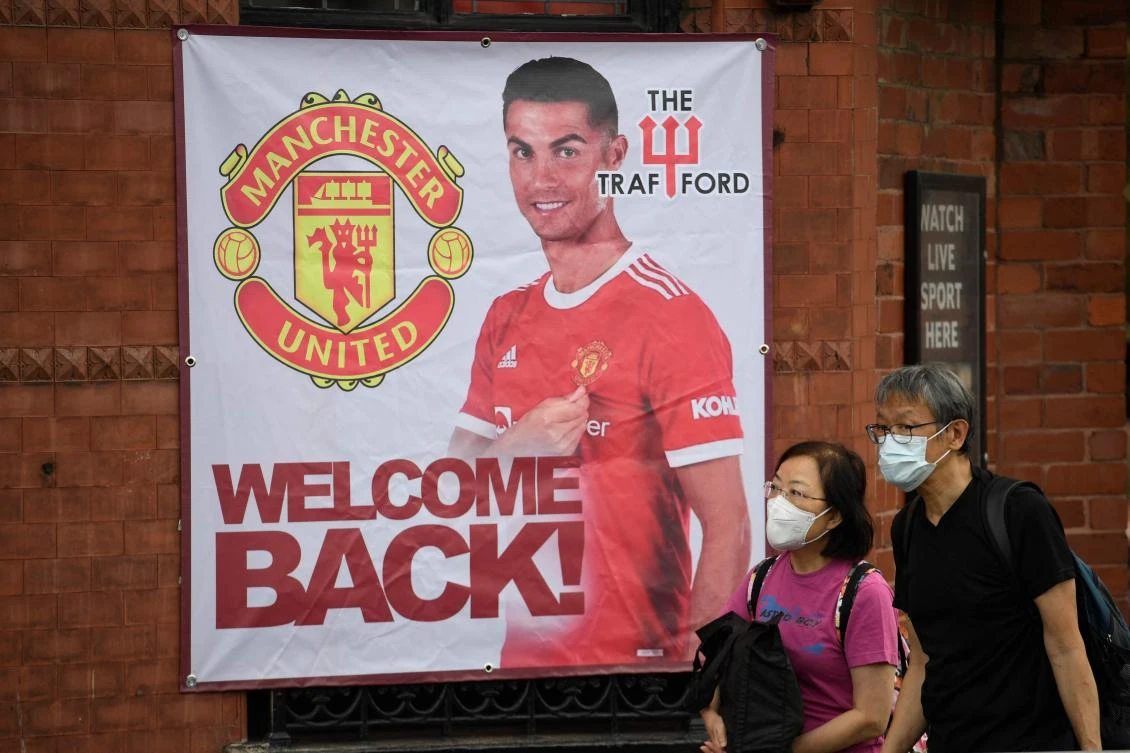 Fans walk past a banner featuring Manchester United’s new signing Cristiano Ronaldo at Old Trafford stadium in Manchester on Friday. (AFP)