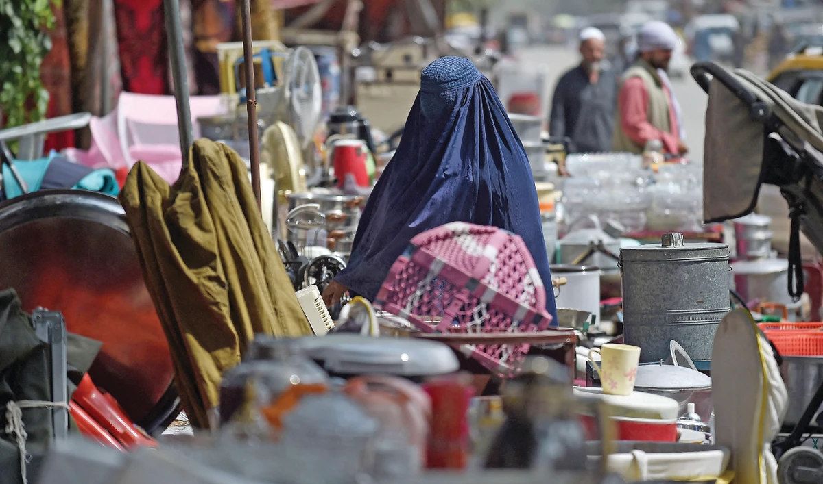 Photo shows a woman looking at secondhand household items for sale at a market in the northwest neighborhood of Khair Khana in Kabul. (AFP)