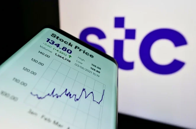 Smartphone with website of Arabian carrier Saudi Telecom Company (STC) on screen in front of company logo. (Shutterstock)