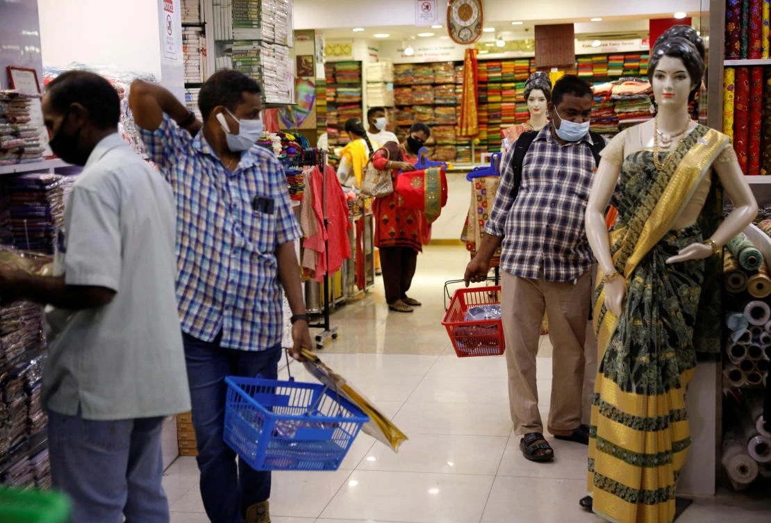 Vairavan Karuppaiah, right, shops at Singapore’s Little India area as part of a pilot program to allow fully vaccinated migrant workers back to the community after more than a year of coronavirus movement curbs. (Reuters)