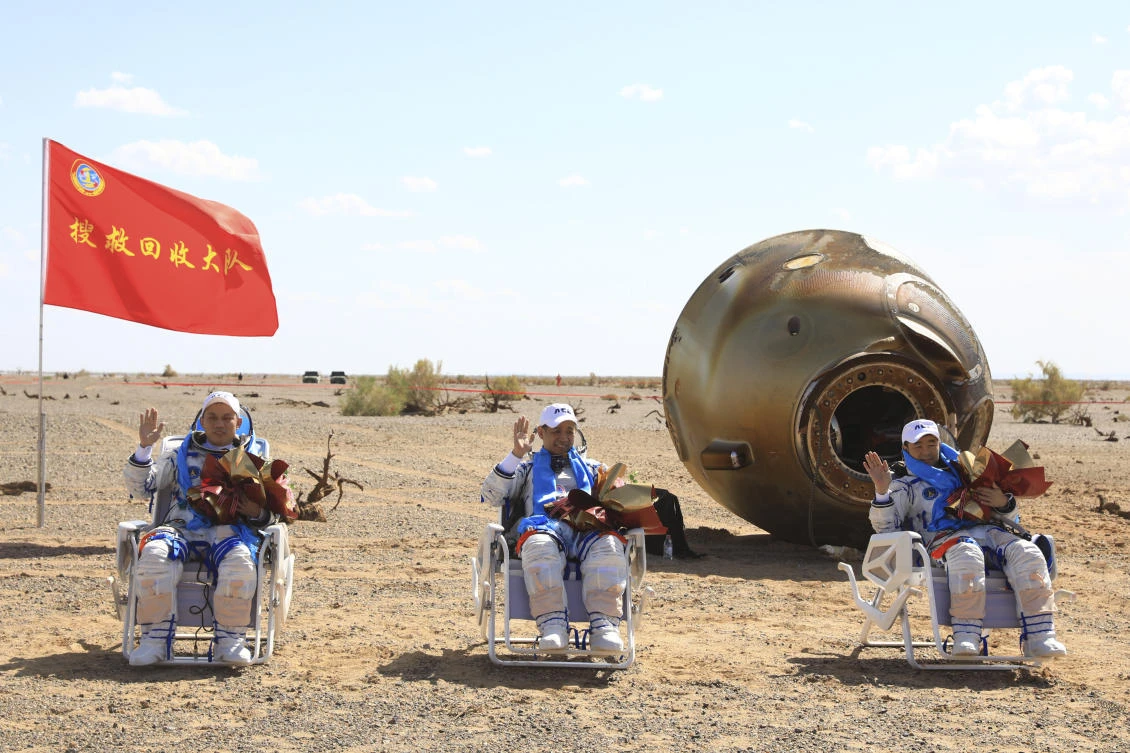 Chinese astronauts from left, Tang Hongbo, Nie Haisheng and Liu Boming wave at the Dongfeng landing site in northern China's Inner Mongolia Autonomous Region on Friday, Sept. 17, 2021. (AP)