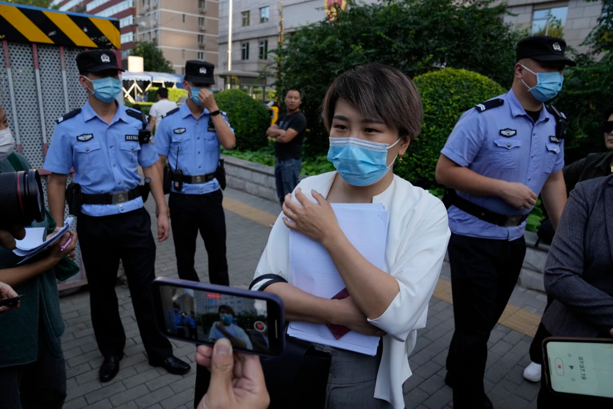 Police keep watch as Teresa Xu speaks to journalists at the end of her court session at the Chaoyang People's Court in Beijing on Sept. 17, 2021. (AP Photo/Ng Han Guan)