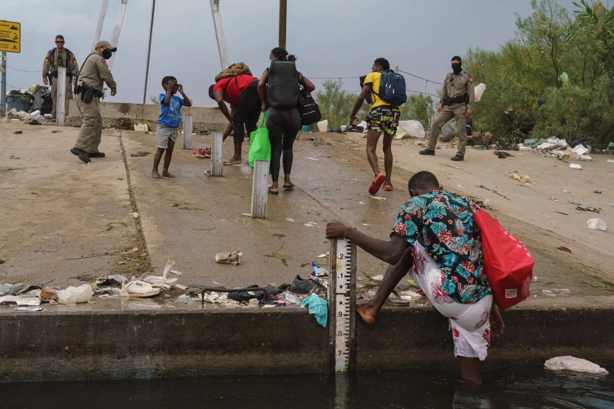 Migrants, many from Haiti, assist each other as they cross the Rio Grande with supplies near the Del Rio-Acuna Port of Entry in Del Rio, Texas, on Sept. 18, 2021. (Photo by PAUL RATJE / AFP)
