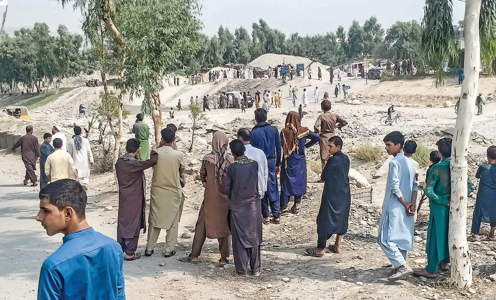 Taliban members and people gather at the site of a bomb explosion which targeted a pickup truck carrying the group’s fighters in Jalalabad on Sunday. (AFP)