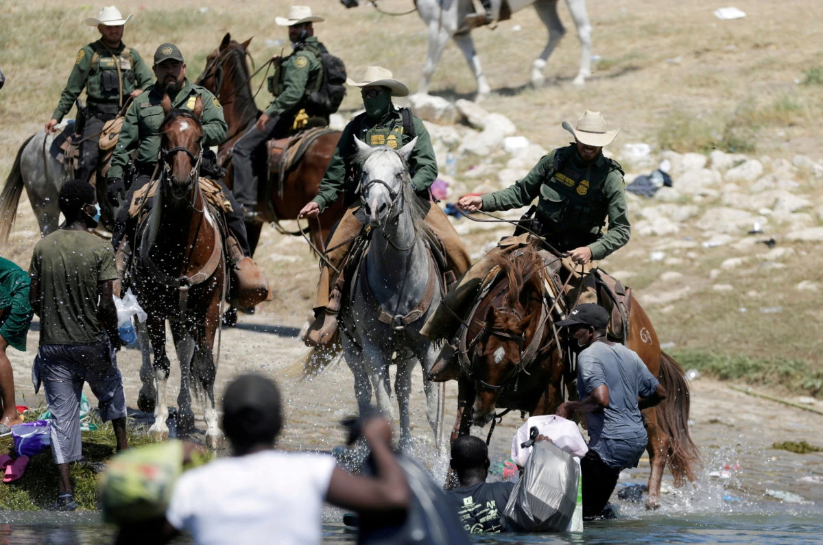 US border patrol officers cut the way of migrants asylum seekers as they are trying to return to the US along the Rio Grande river, after having crossed back into Mexico to buy food, on Sept. 19, 2021. (REUTERS)