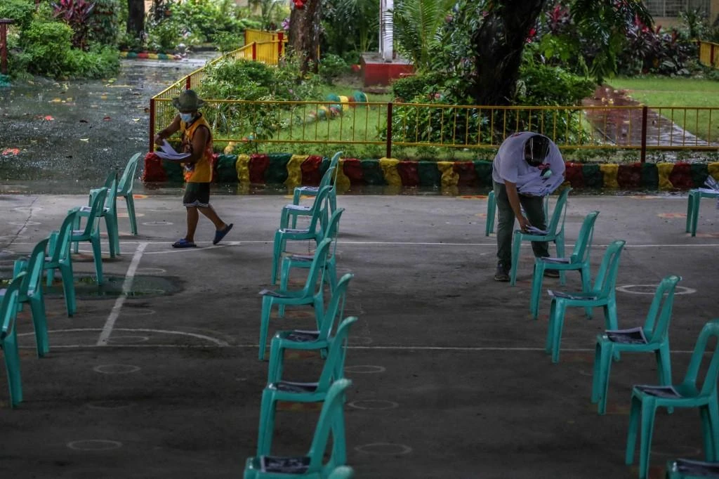 A teacher, right, and volunteer sort distance learning materials to be picked up by parents at a school in Quezon City on Sept. 8, 2021. (AFP)
