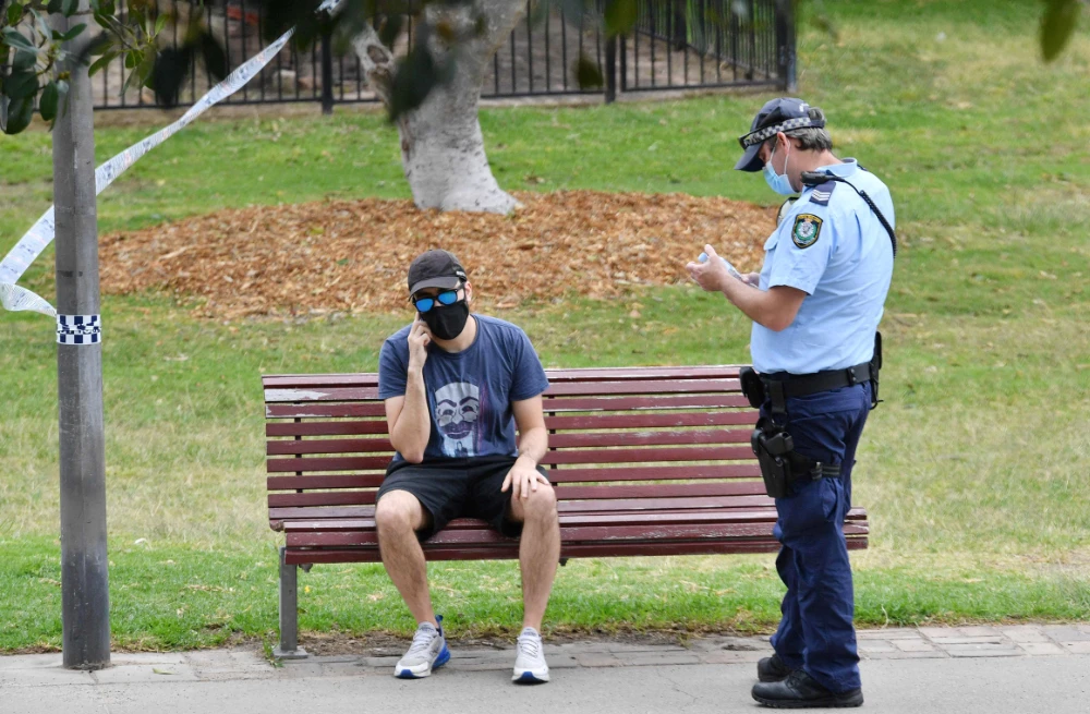 A police officer interacts with a man at Sydney Park on September 18, 2021, following calls for an anti-lockdown protest rally amid the coronavirus pandemic. (AFP)