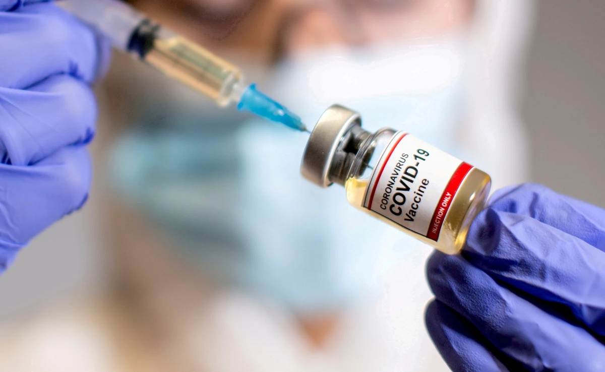 A woman holds a small bottle labelled with a "Coronavirus COVID-19 Vaccine" sticker and a medical syringe in this illustration taken October 30, 2020. (Reuters)