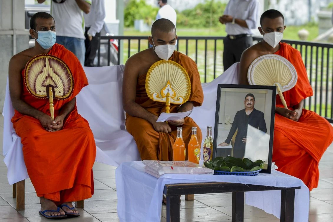 Buddhist monks perform the last rites during the funeral of Eliyantha White, a local shaman who died of the COVID-19. (AFP)