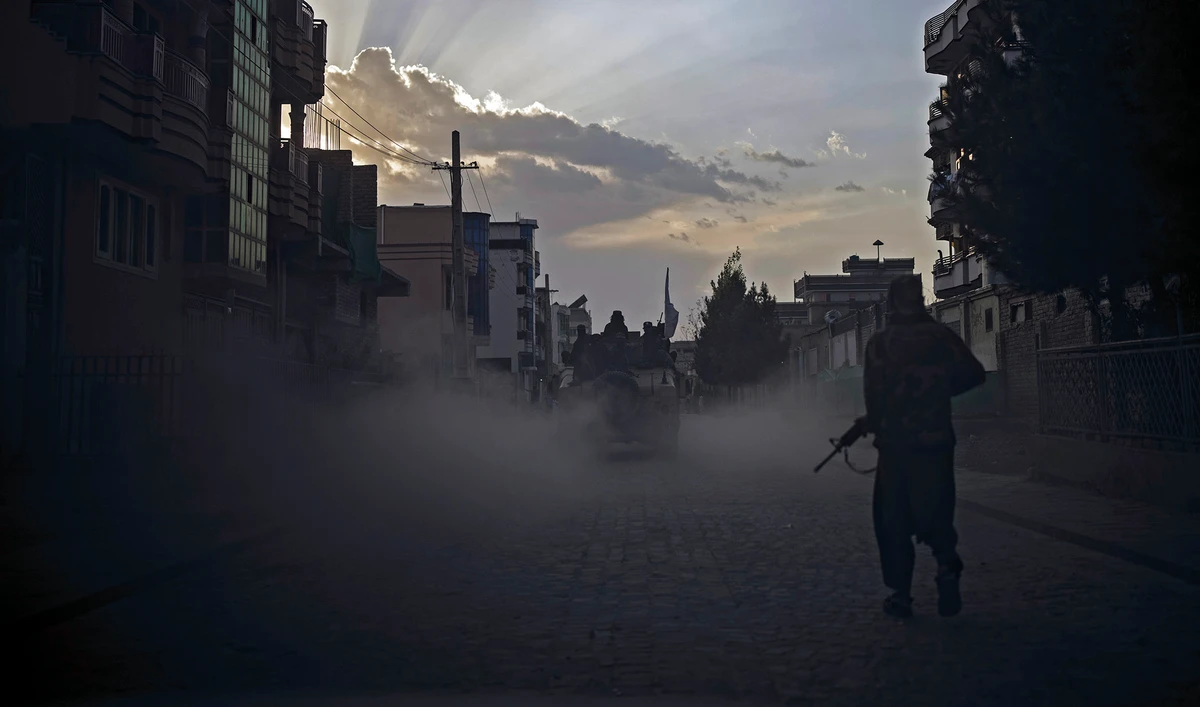 A Taliban fighter walks on the side of a road as a Humvee carrying other fighters drives by in Kabul, Afghanistan on September 21, 2021. (AP)