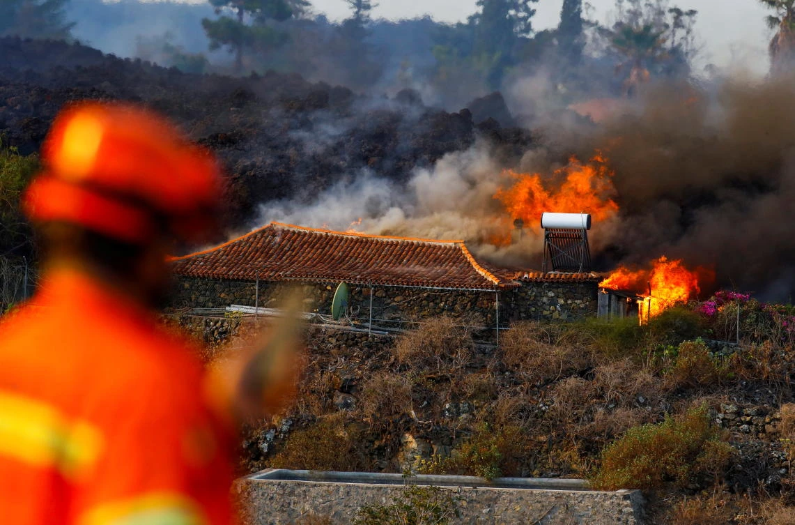 A member of Civil Protection watches as a house burns due to lava from the eruption of a volcano in the Cumbre Vieja national park, in Los Campitos at Los Llanos de Aridane, on the Canary Island of La Palma. (Reuters)