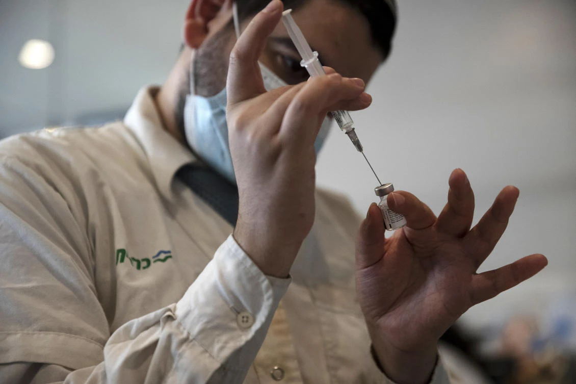 A medical worker prepares a vial of the Pfizer coronavirus vaccine at Clalit Health Service's center in the Cinema City complex in Jerusalem, Wednesday, Sept. 22, 2021.(AP)
