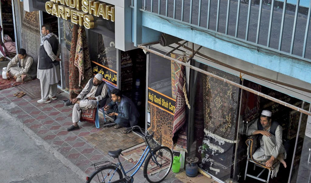 Afghan carpet vendors sit beside their shop as they wait for customers at Chicken Street in Kabul on September 26, 2021. (AFP)