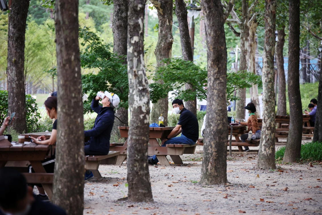 People rest as they keep social distancing to avoid the spread of the coronavirus disease at a park in Seoul, South Korea on Sept. 27, 2021. (Reuters)