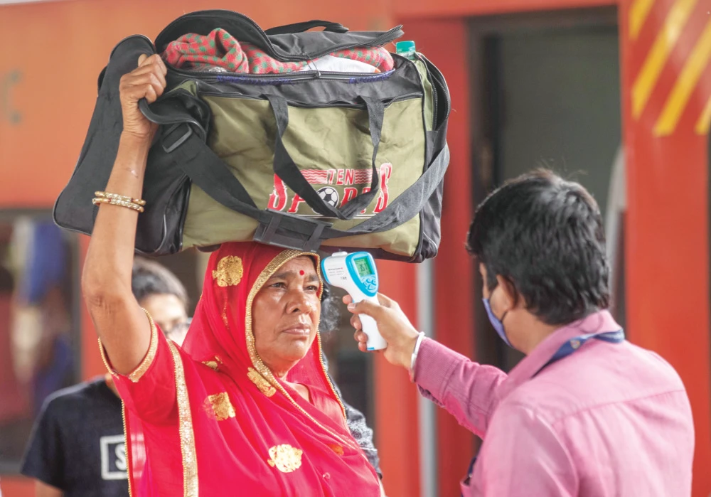 A health worker checks body temperature of a traveler as a precaution against COVID-19 before allowing her to proceed at a train station in Mumbai Thursday. (AP)