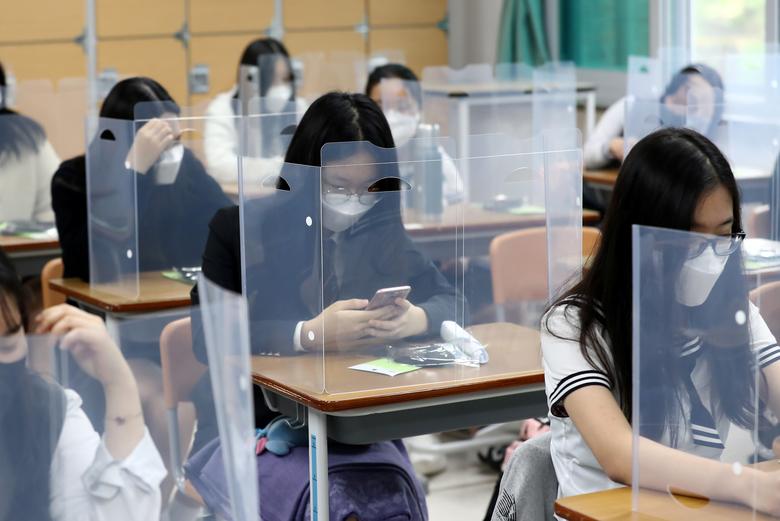 High school students wearing face masks prepare for class, with plastic shields on their desks, Daejeon, South Korea, May 20, 2020. (Reuters)