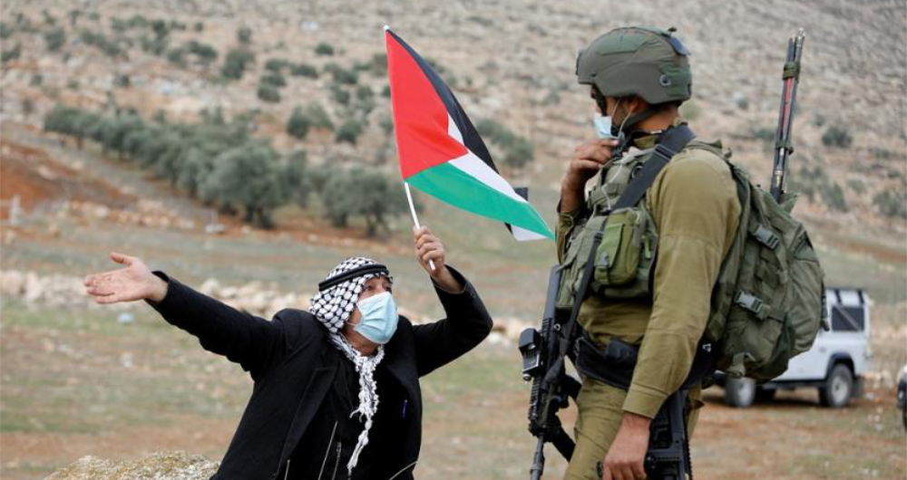 A demonstrator holds a Palestinian flag in front of an Israeli soldier during a protest against Jewish settlements in Beit Dajan in the Israeli-occupied West Bank. (Reuters/File)