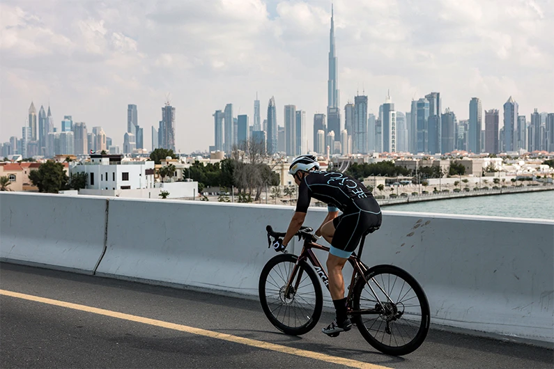 A cyclist rides along a road in Dubai on November 24, 2020, as the Burj Khalifa, the world's tallest skyscraper, is seen in the skyline behind. (AFP)