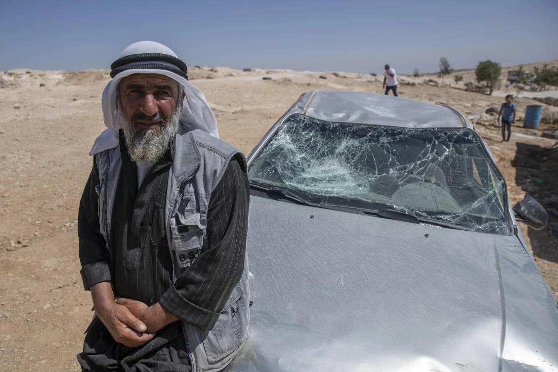 A Palestinian man leans on his smashed vehicle, following a settlers attack from nearby settlement outposts, in the West Bank village of Al-Mufagara, near Hebron, Sept. 30, 2021. (AP Photo)