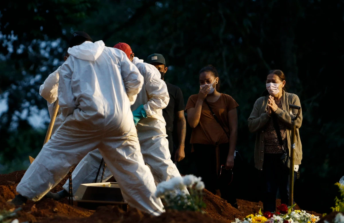 In this file photo taken on April 17, 2021 people mourn as a COVID-19 victim is buried by cemetery workers at the Vila Formosa cemetery in Sao Paulo, Brazil. (AFP)