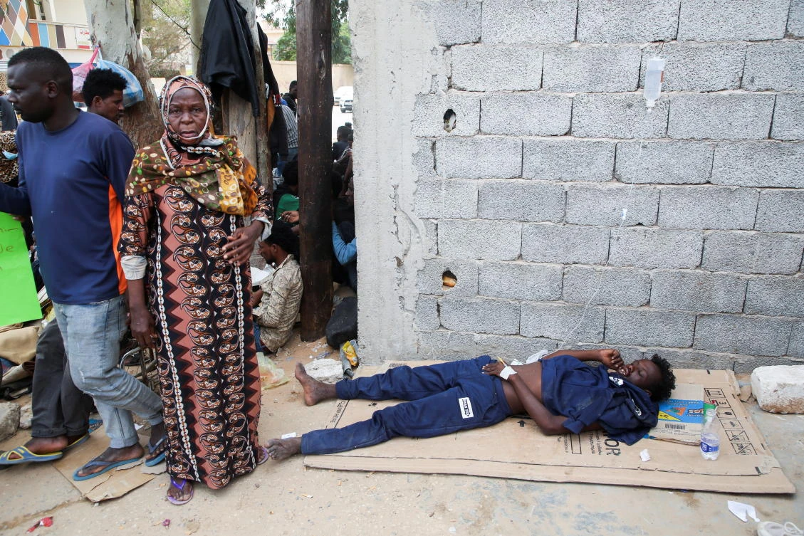 A migrant receives IV treatment in makeshift care area as migrants wait outside the United Nations High Commissioner for Refugees (UNHCR) negotiation office, in Tripoli, Libya, October 9, 2021. (Reuters)