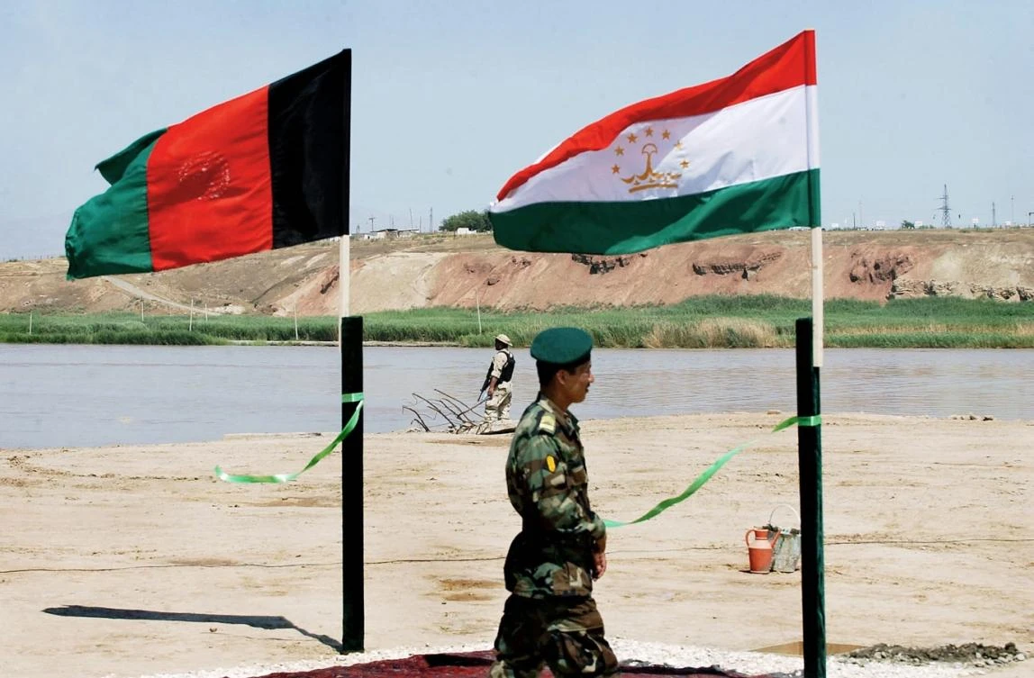 An Afghan National Army soldier passes the flags of Afghanistan (L) and Tajikistan during a ceremony for a new US-funded bridge linking Afghanistan and Tajikistan over the Pyanzh river. (File/AFP)