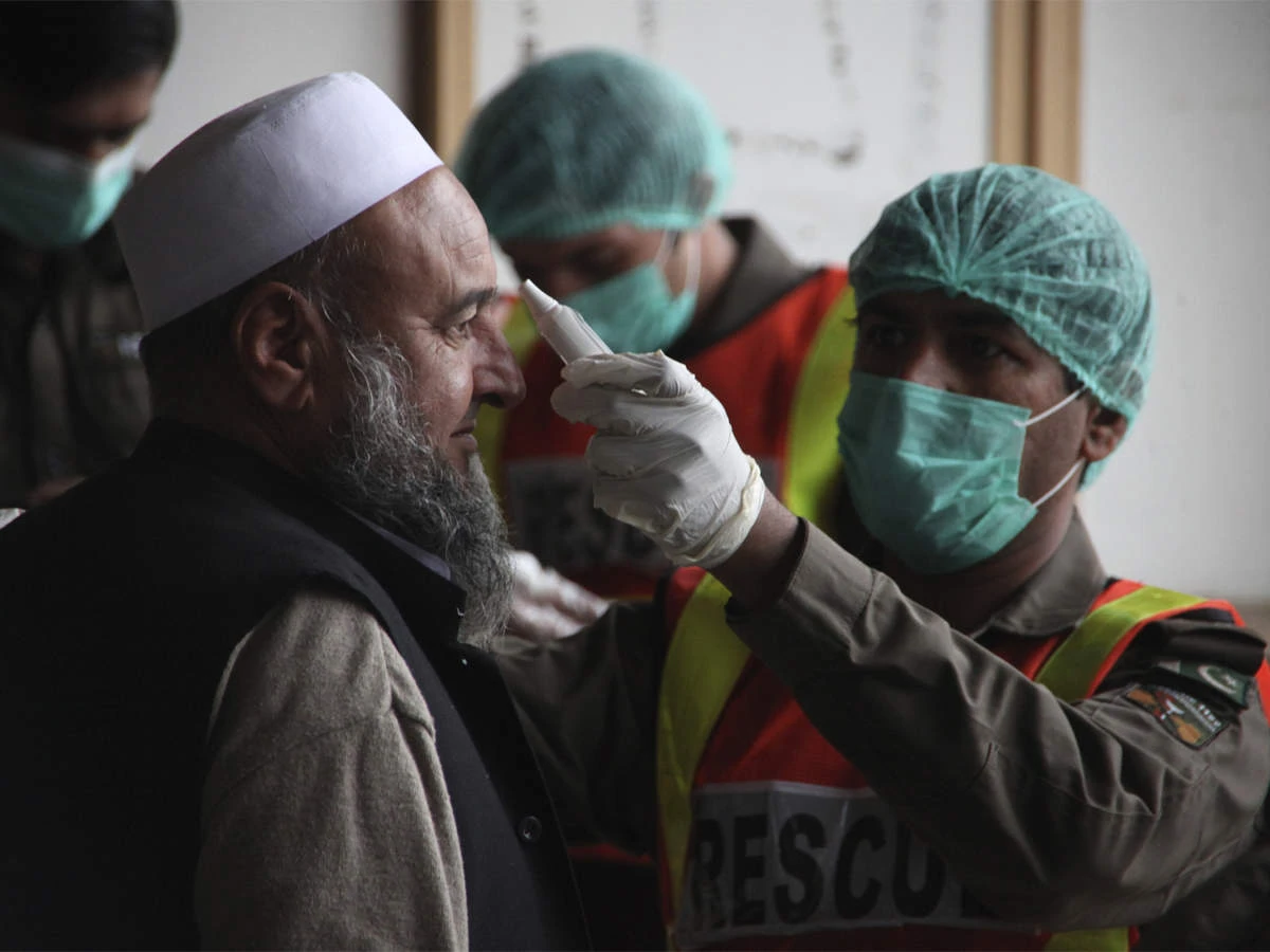 A healthcare worker checks the temperature of a man in a hospital in Karachi, Pakistan. (AP)