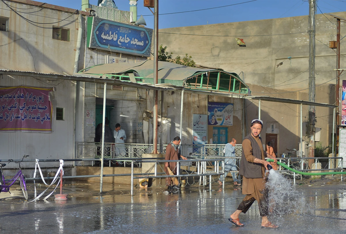 A man sprays water with a hose to clean a street outside a Shiite mosque in Kandahar, Afghanistan, on October 15, 2021. (AFP)