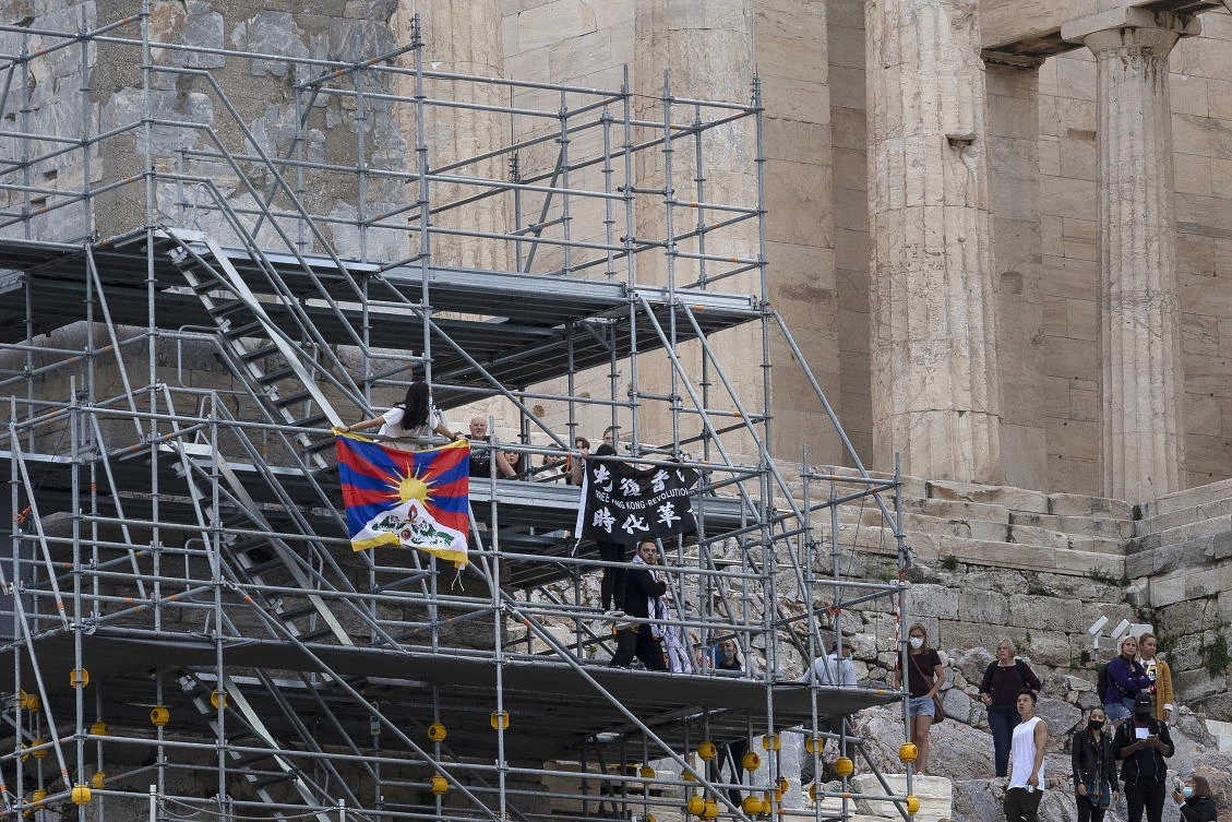 Activists raise a Tibetan flag and a banner from scaffolding at the Acropolis hill, in Athens on Oct. 17, 2021. (AP)